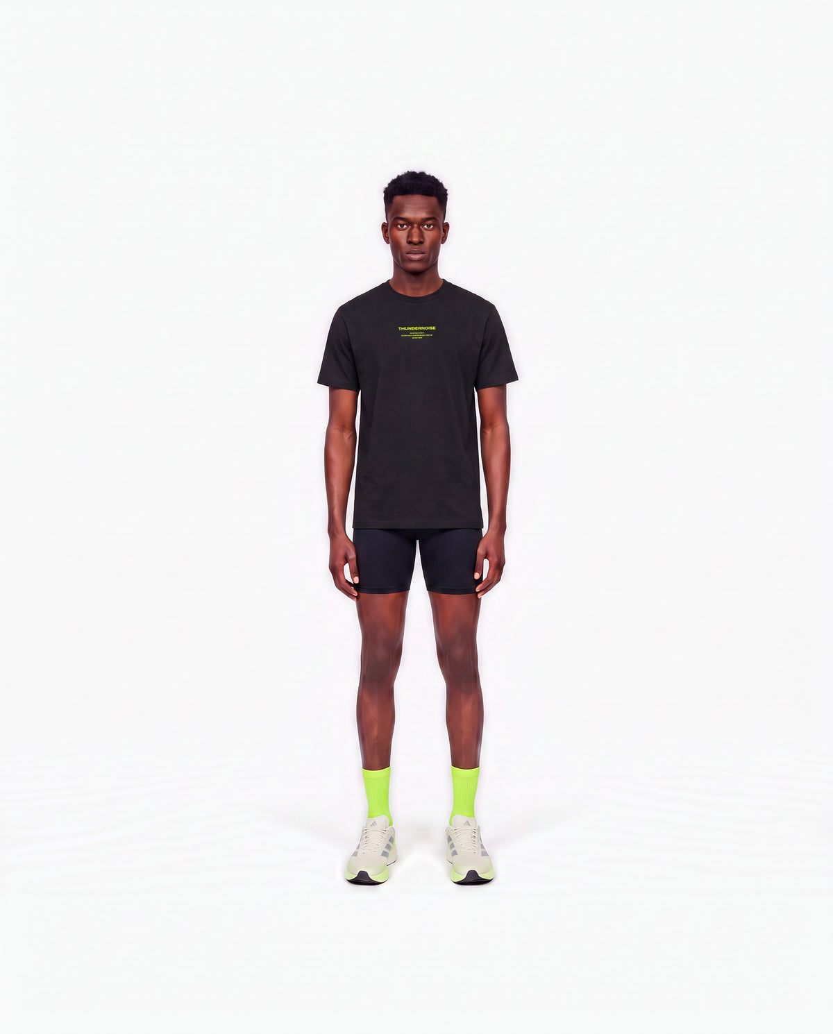 Model wearing the Brick by Brick t-shirt in black — front view with the THUNDERNOISE TRAINING DEPT block centred on the chest in lime green — View 2