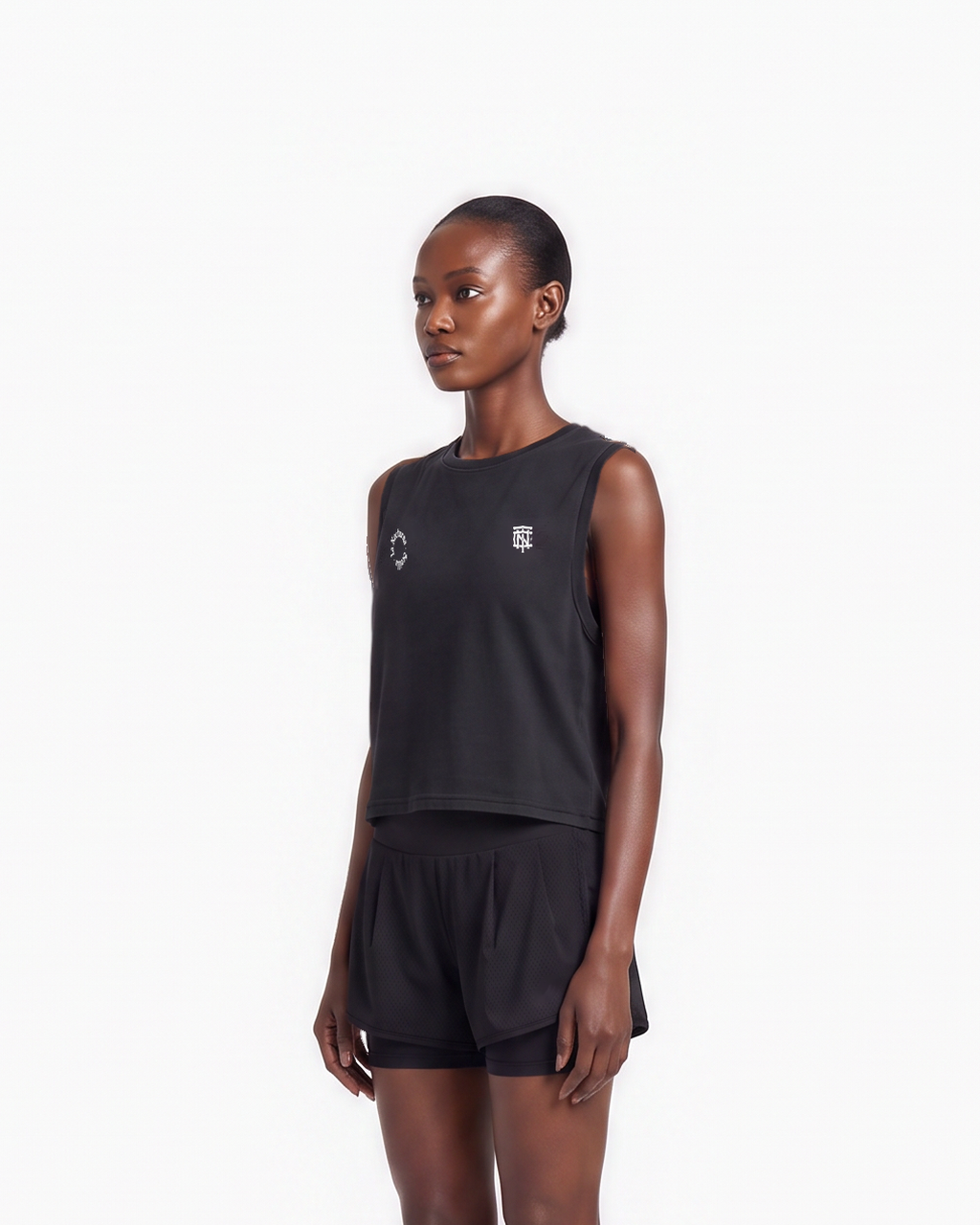 Model wearing the Let's Run the Night cropped tank top in black — three-quarter view, close crop on the cropped fit — View 5