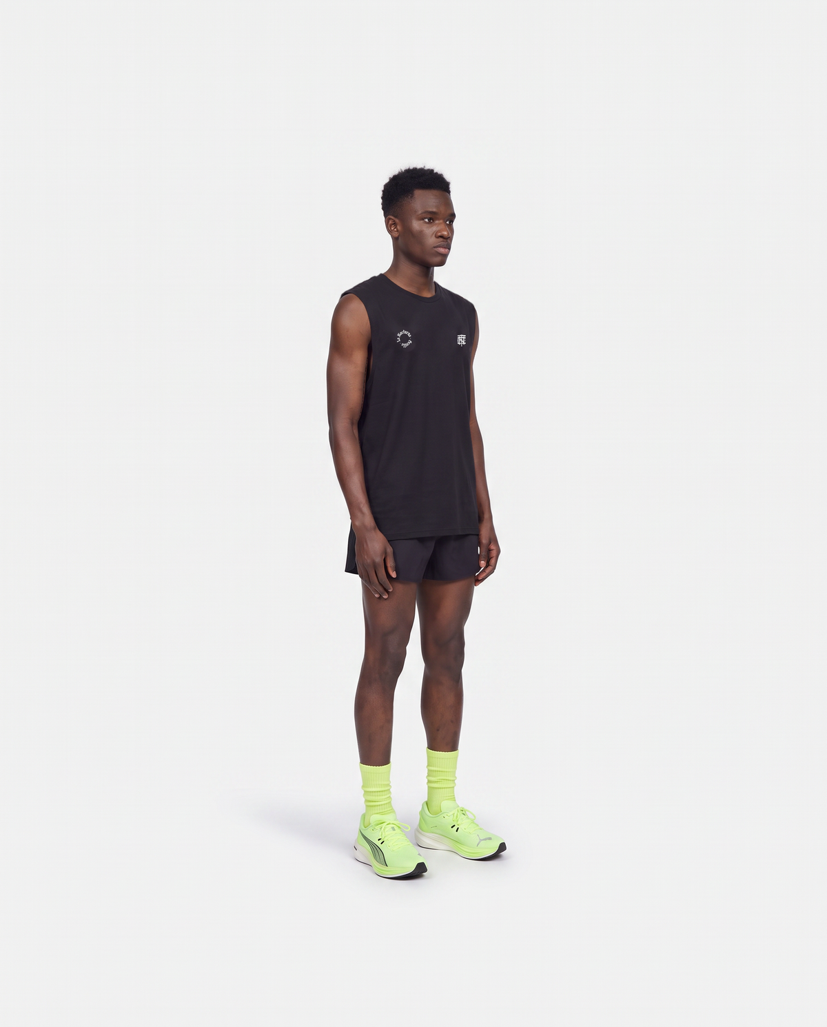 Model wearing the Let's Run the Night tank top in black — three-quarter view showing the regular fit — View 4
