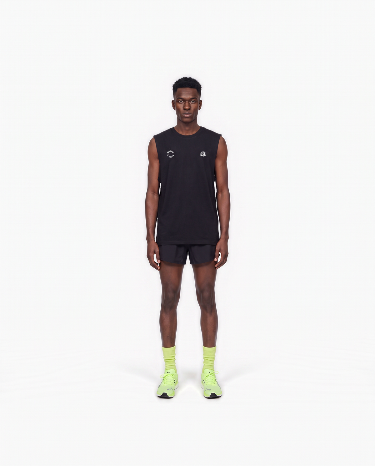 Model wearing the Let's Run the Night tank top in black — front view with the La Nocturna Sevilla seal and the TN monogram in white — View 2