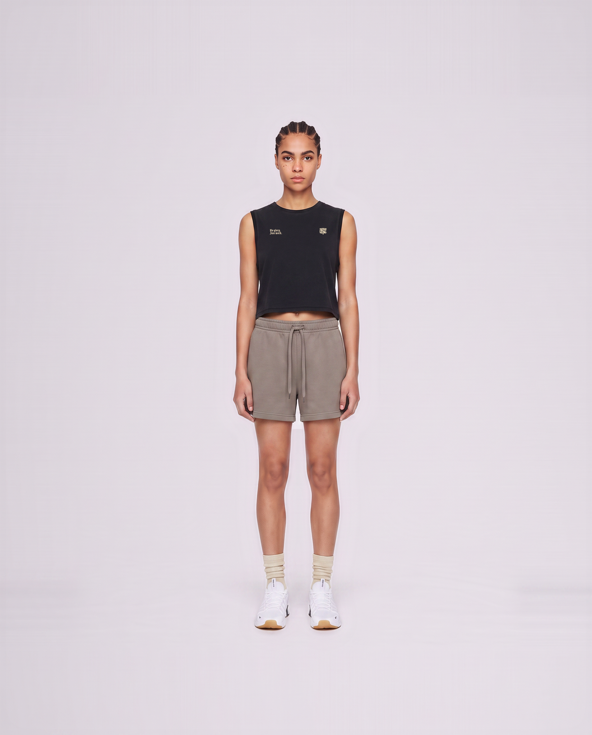 Model wearing the No Glory Just Work cropped tank top in black — front view with the left-chest NO GLORY JUST WORK wordmark and the right-chest Thundernoise monogram in sand — View 2