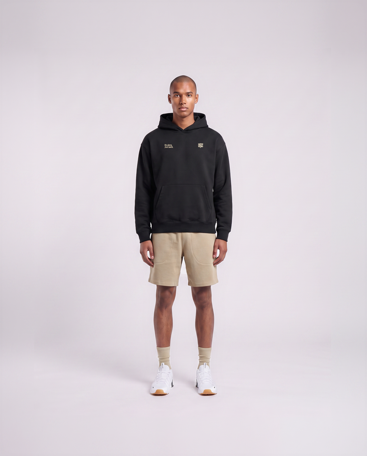 Model wearing the No Glory Just Work oversize hoodie in black — front view with the left-chest NO GLORY JUST WORK wordmark and the right-chest Thundernoise monogram in sand — View 2