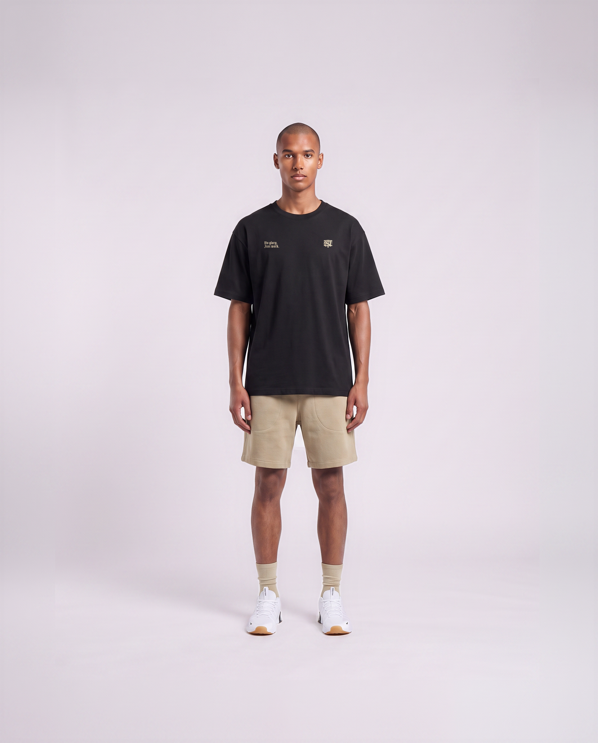 Model wearing the No Glory Just Work oversize t-shirt in black — front view with the left-chest NO GLORY JUST WORK wordmark and the right-chest Thundernoise monogram in sand — View 2