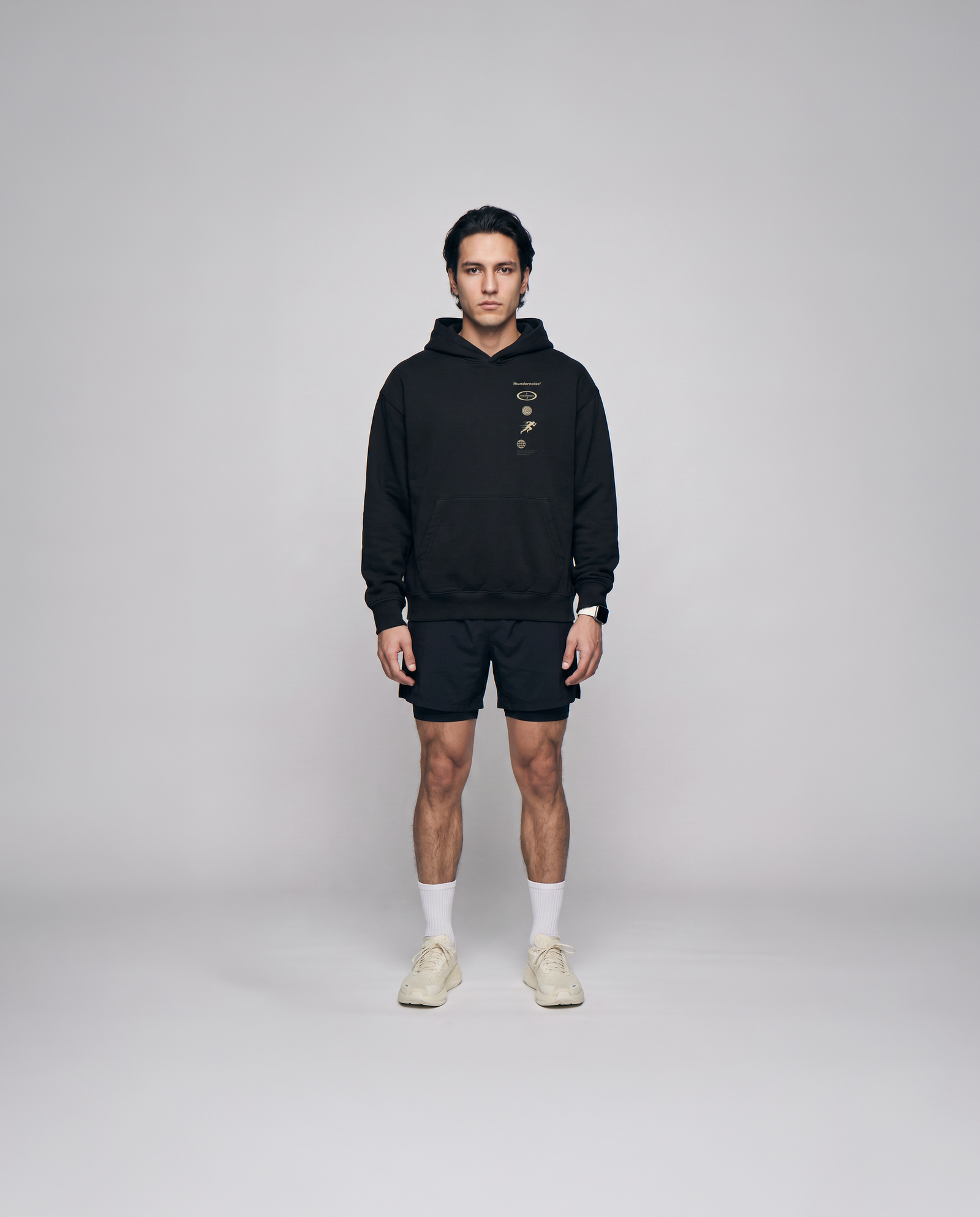 Model wearing the Strong Enough to Run oversize hoodie in black — front view with the right-chest marker column in sand and grey — View 4