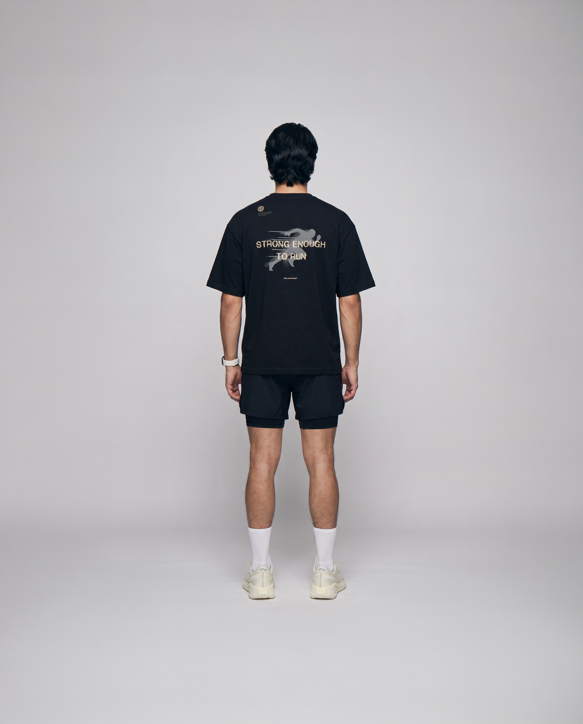 Model wearing the Strong Enough to Run oversize t-shirt in black — back view with the STRONG ENOUGH TO RUN halftone runner print — View 3