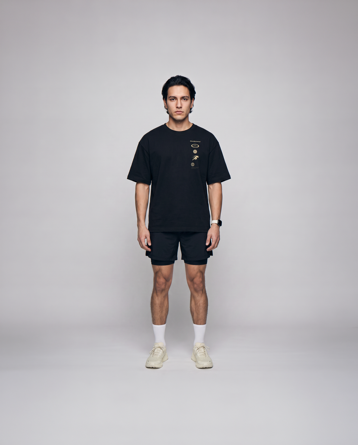Model wearing the Strong Enough to Run oversize t-shirt in black — front view with the right-chest marker column in sand and grey — View 4