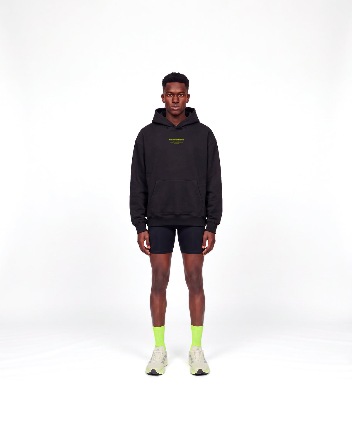 Model wearing the Brick by Brick oversize hoodie in black — front view with the THUNDERNOISE TRAINING DEPT block centred on the chest in lime green — View 2
