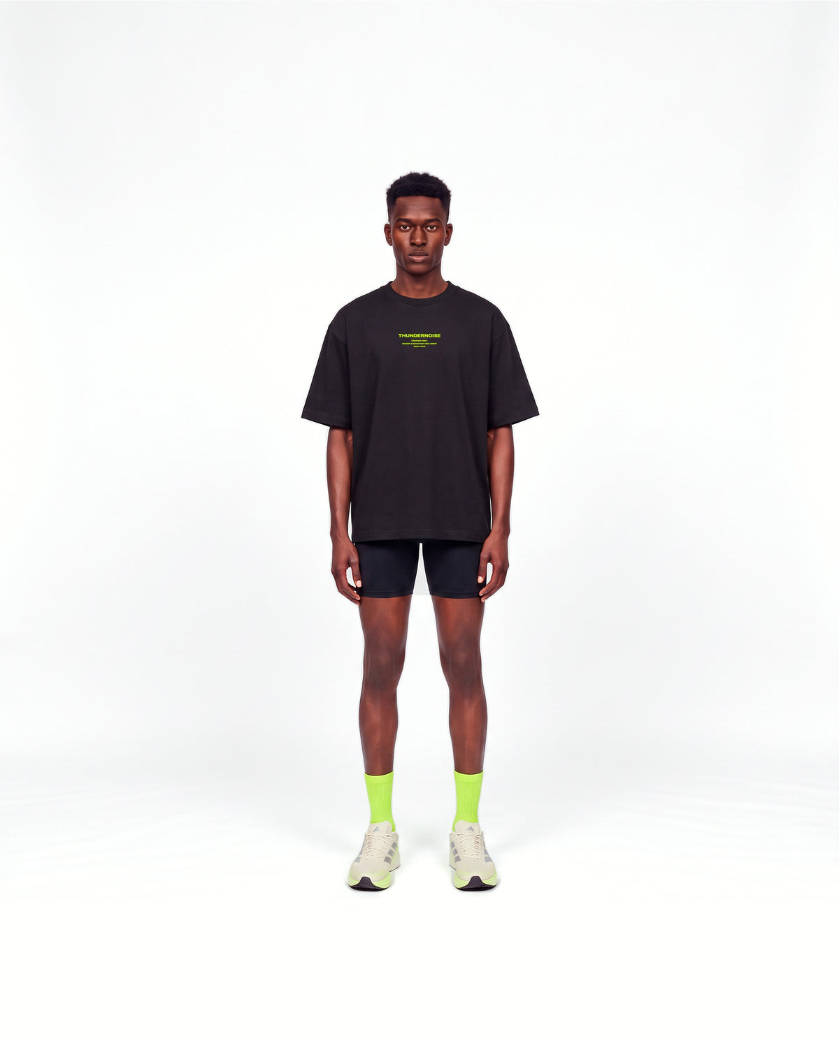 Model wearing the Brick by Brick oversize t-shirt in black — front view with the THUNDERNOISE TRAINING DEPT block centred on the chest in lime green — View 2
