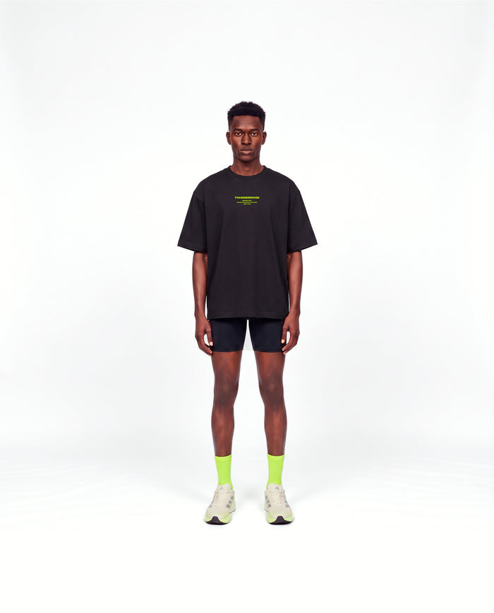 Model wearing the Brick by Brick oversize t-shirt in black — front view with the THUNDERNOISE TRAINING DEPT block centred on the chest in lime green