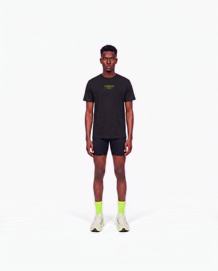 Model wearing the Brick by Brick t-shirt in black — front view with the THUNDERNOISE TRAINING DEPT block centred on the chest in lime green