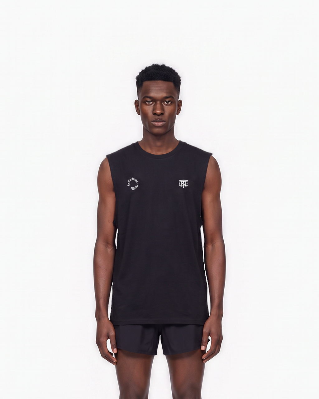 Model wearing the Let's Run the Night tank top in black — front view, close crop on the La Nocturna Sevilla seal and the TN monogram in white — View 3

