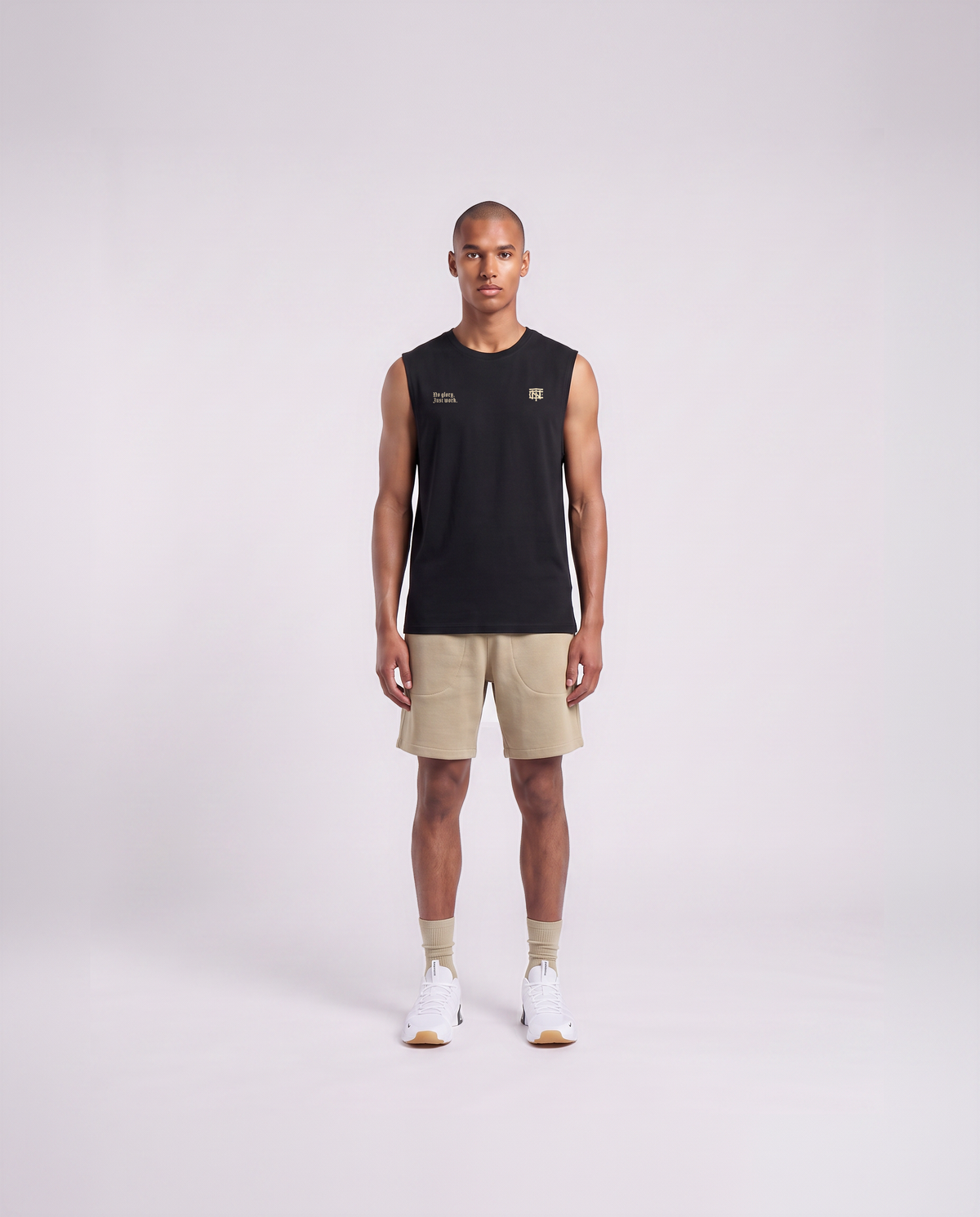 Model wearing the No Glory Just Work tank top in black — front view with the left-chest NO GLORY JUST WORK wordmark and the right-chest Thundernoise monogram in sand — View 2
