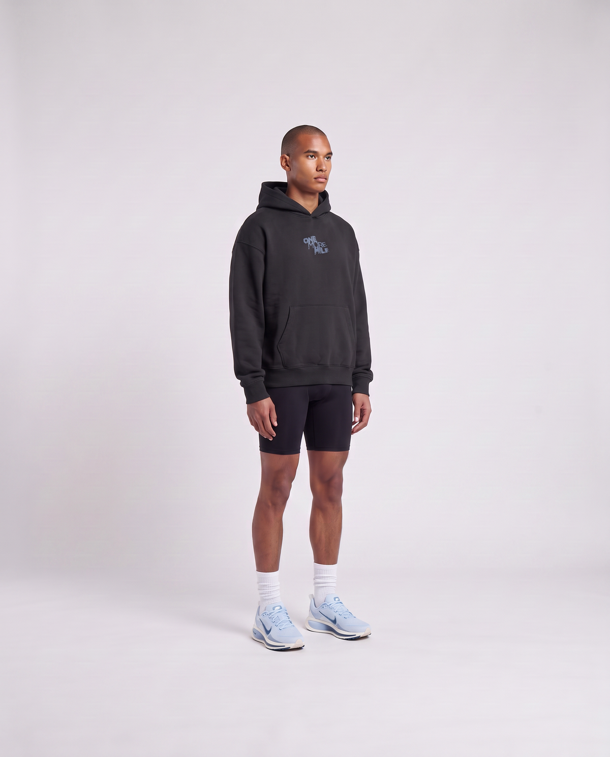 Model wearing the One More Mile oversize hoodie in black — three-quarter view showing the oversize fit