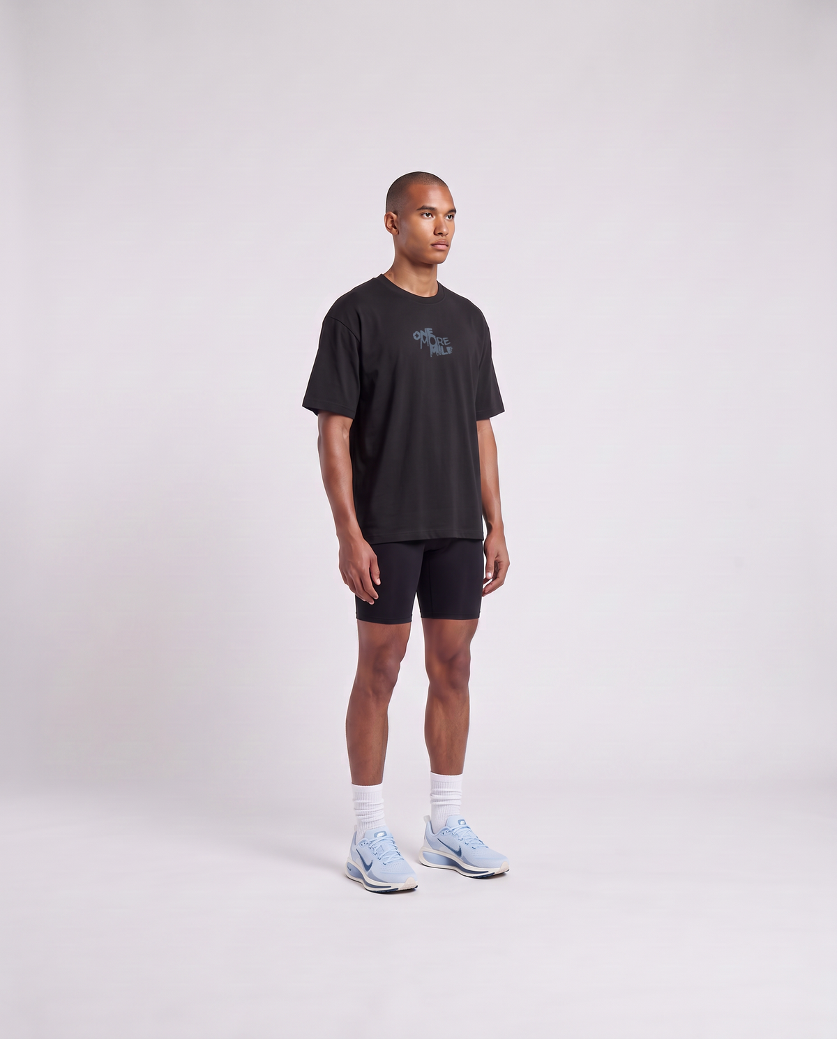 Model wearing the One More Mile oversize t-shirt in black — three-quarter view showing the oversize fit