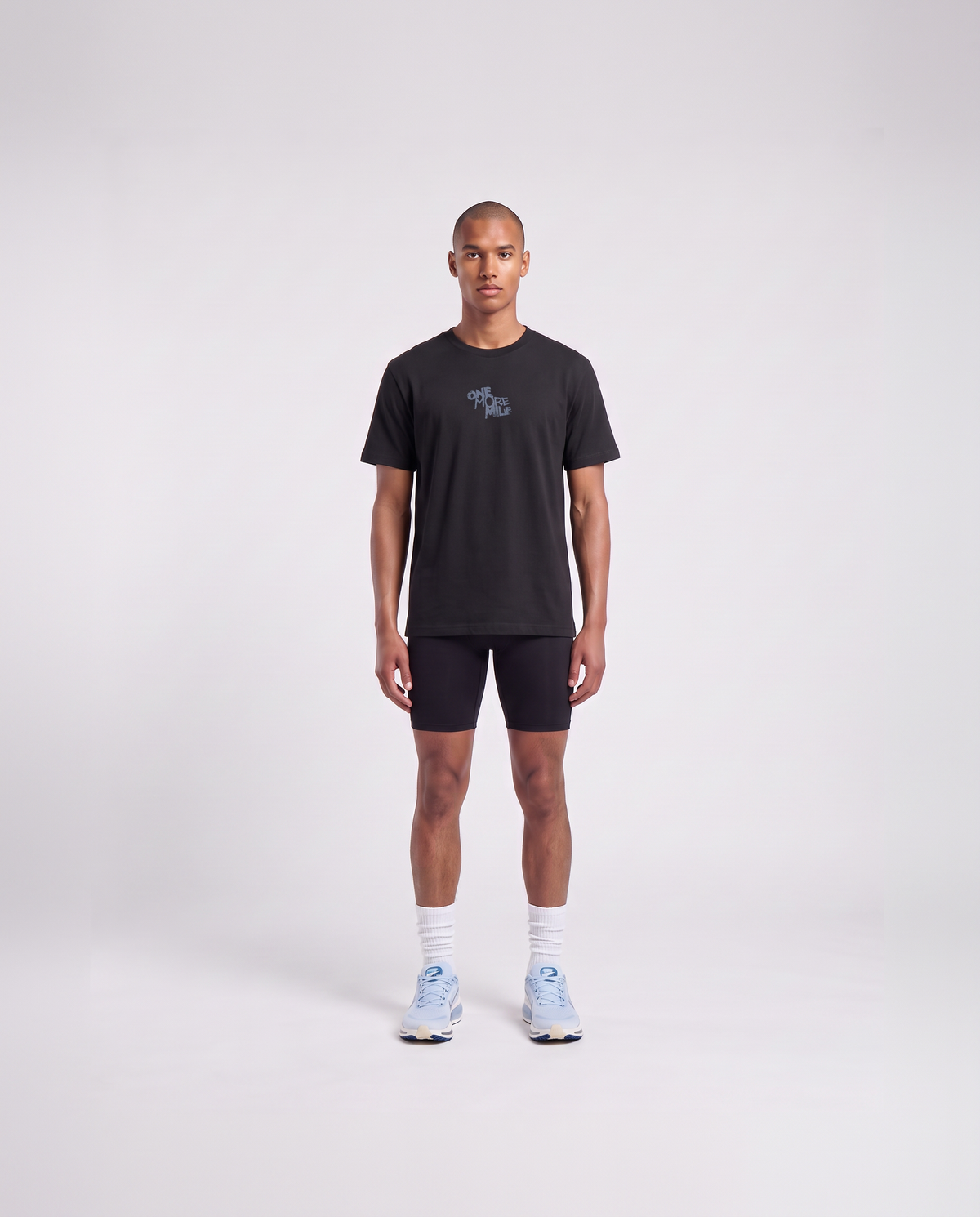 Model wearing the One More Mile t-shirt in black — front view with the ONE MORE MILE graffiti mark at the chest in slate blue