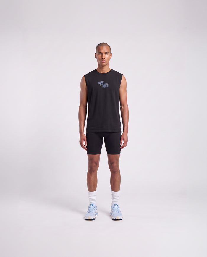 Model wearing the One More Mile tank top in black — front view with the ONE MORE MILE graffiti mark at the chest in slate blue