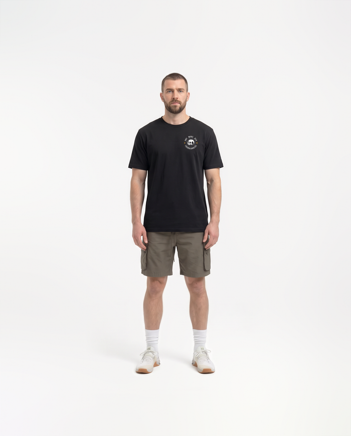 Model wearing the One More Rep t-shirt in black — front view with the halftone skull seal ringed by ONE MORE REP at the left chest