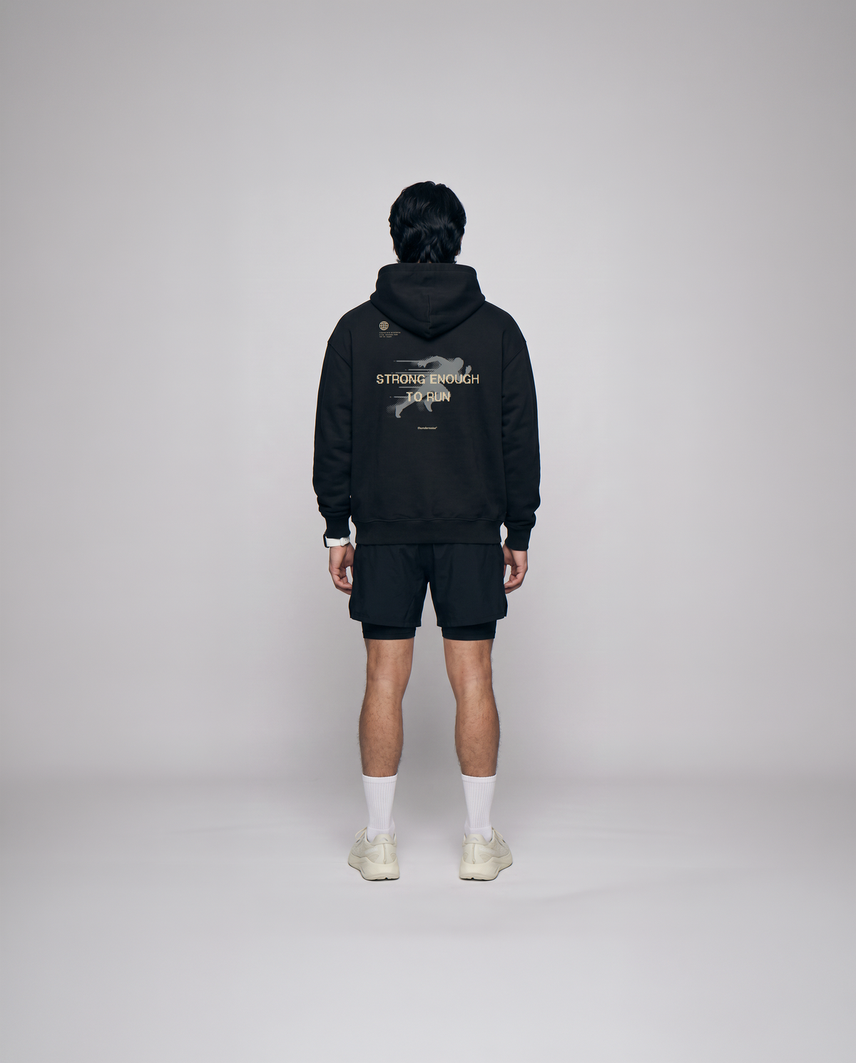 Model wearing the Strong Enough to Run oversize hoodie in black — back view with the STRONG ENOUGH TO RUN halftone runner print — View 3
