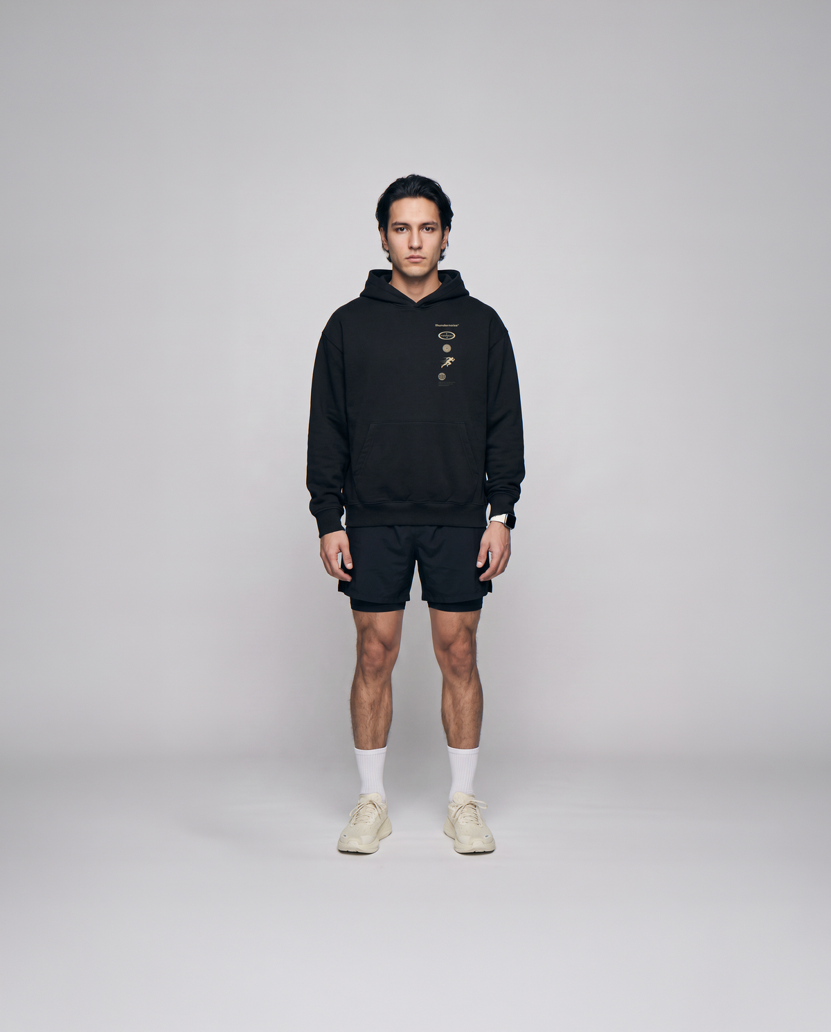 Model wearing the Strong Enough to Run oversize hoodie in black — front view with the right-chest marker column in sand and grey — View 4
