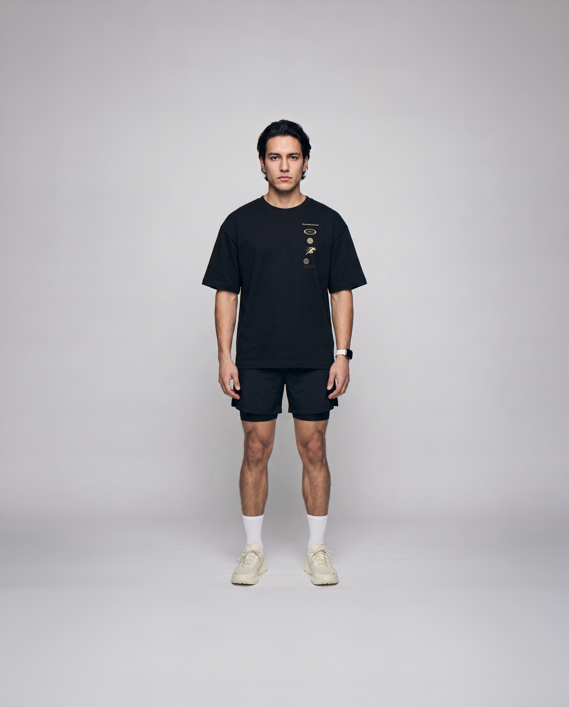 Model wearing the Strong Enough to Run oversize t-shirt in black — front view with the right-chest marker column in sand and grey